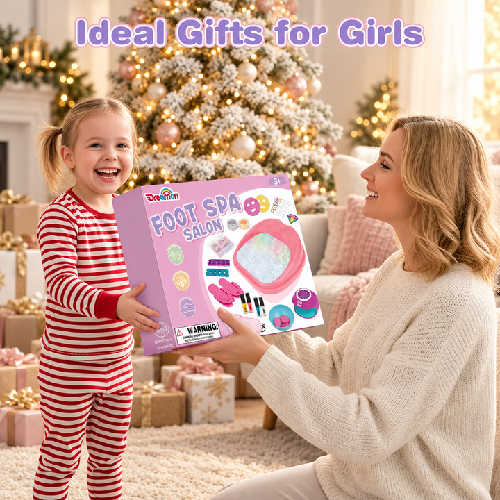 A woman and a young girl in red and white striped pajamas are smiling while holding a pink Dreama Foot Spa Salon toy kit box in a cozy living room decorated for Christmas.