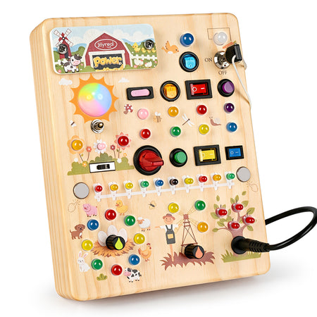 A wooden sensory motor board toy with colorful buttons, knobs, and farm-themed illustrations, shown on a white background with its power cord plugged in.